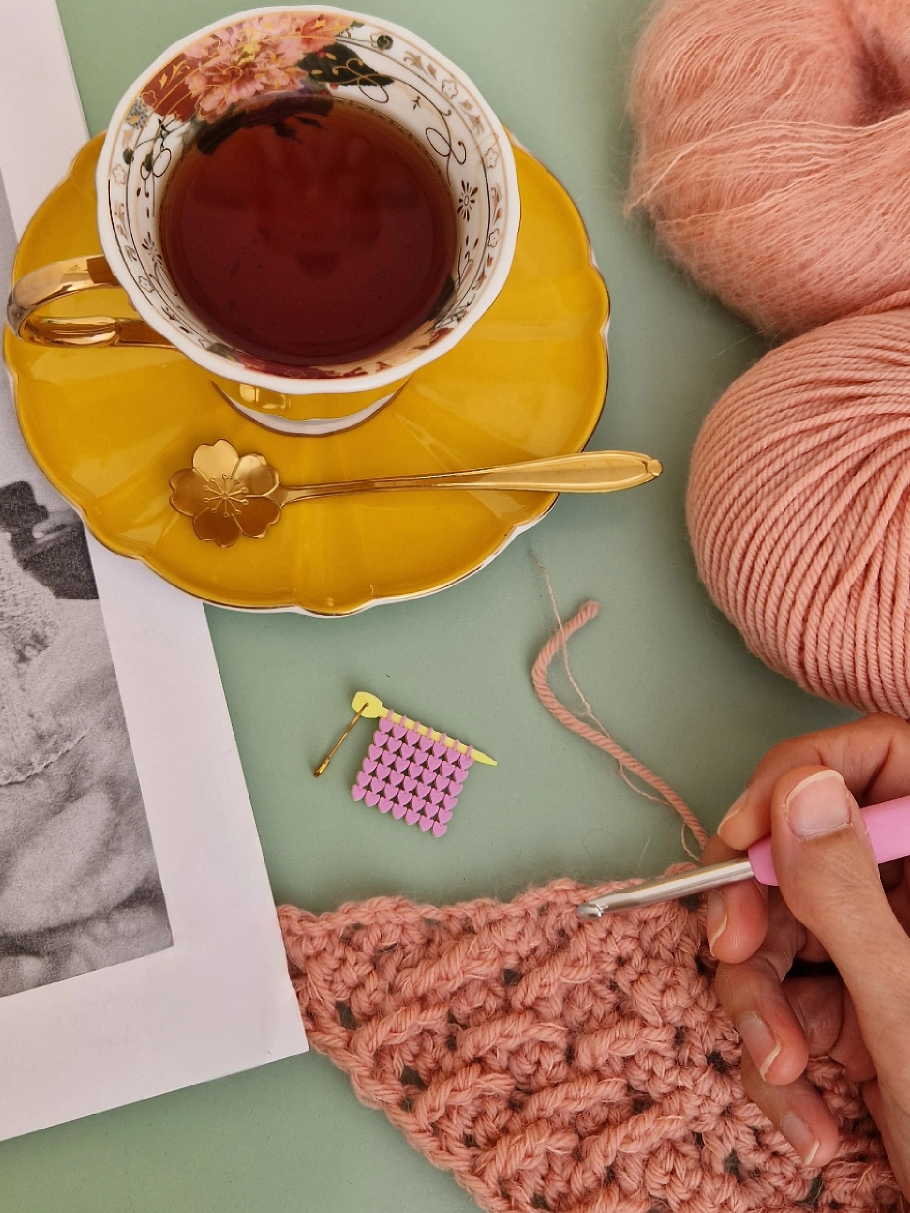 Cup of tea, pink yarn and crochet work with a handmade Mostacita Moraíta stitch marker